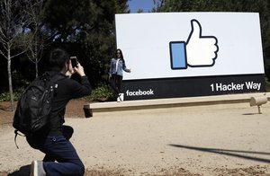 Visitors take photos in front of the Facebook logo at the company's headquarters Wednesday, March 28, 2018, in Menlo Park , Calif.