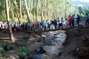 Residents cross a river filled with mud in Bududa District, Uganda, Friday, Oct. 12, 2018.