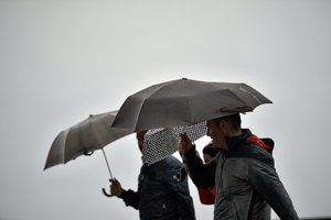 A weakened hurricane Leslie as people shelter from the rain under their umbrellas, oast of Portugal