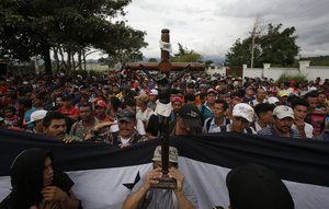 A Honduran migrant holds up a replica of the Black Christ of Esquipulas as Guatemalan police temporarily block the road after the caravan crossed the Honduras-Guatemala border without incident, in Esquipulas, Guatemala, Monday, Oct. 15, 2018.