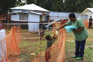 In this photo taken Sunday, Sept 9, 2018, a health worker, right, feeds a boy suspecting of having the Ebola virus at an Ebola treatment centre in Beni, Eastern Congo.