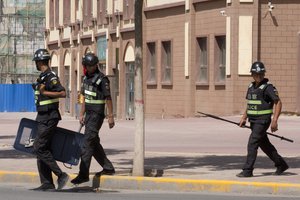 File - Policemen patrol the streets of Peyzawat, western China's Xinjiang region on Friday, Aug. 31, 2018.