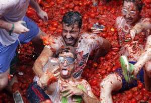 Revelers take pictures as they enjoy throwing tomatoes at each other, during the annual "Tomatina", tomato fight fiesta, in the village of Bunol, 50 kilometers outside Valencia, Spain, Wednesday, Aug. 30, 2017.