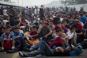 Migrants bound for the U.S.-Mexico border wait on a bridge that stretches over the Suchiate River, connecting Guatemala and Mexico, in Tecun Uman, Guatemala, early Saturday, Oct. 20, 2018.