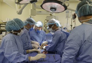 In this Aug. 6, 2014 photo, Dr. Faran Bokhari, head of the trauma department at Cook County’s Stroger Hospital in Chicago, second from right, and Dr. Jared Bernard, a lieutenant commander and trauma surgeon in the U.S. Navy, third from left, work together during surgery of a gunshot victim