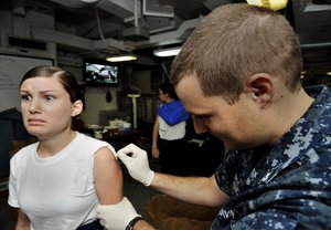 A Sailor is vaccinated by Hospital Corpsman 2nd Class Christopher LeBlanc aboard the Nimitz-class aircraft carrier USS Harry S. Truman (CVN 75).