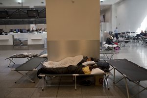 Passengers sleep on cots set up in the departures hall of the Zaventem international airport during a luggage handling workers strike in Brussels, Friday, Oct. 26, 2018.