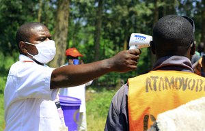 Healthcare worker left, takes a body temperature of a man in  Mangina Democratic Republic of Congo, Wednesday, Aug 8, 2018.