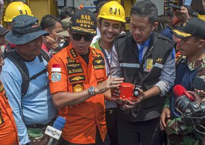 Chief of National Search and Rescue Agency Muhammad Syaugi, center, holds the flight data recorder from the crashed Lion Air jet during a press conference, onboard rescue ship anchored in the waters of Tanjung Karawang, Indonesia, Thursday, Nov. 1, 2018.