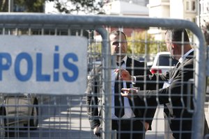 Seen behind barriers blocking the road leading to the Saudi Arabia Consulate, security guards stand in Istanbul, Friday, Oct. 26, 2018. The Saudi officials who killed journalist Jamal Khashoggi in their Istanbul consulate must reveal the location of his body, Turkey's President Recep Tayyip Erdogan said Friday.