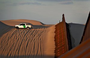 A U.S. Customs and Border Patrol agent patrols a section of floating fence at sunset that runs through Imperial Sand Dunes Wednesday, July 18, 2018 along the international border with Mexico in Imperial County, Calif.