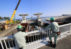 Workers look at a floodgate under construction after tsunami warning was lifted after 7.4 powerful earhquake in Iwaki, Fukushima prefecture, northeastern Japan