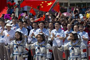 China's astronauts from left, Wang Yaping, Zhang Xiaoguang and Nie Haisheng wave to the media as they leave the Jiuquan satellite launch center near Jiuquan in western China's Gansu province, Tuesday, June 11, 2013