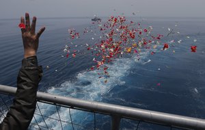 A relative sprinkles flowers during a prayer for the victims of the crashed Lion Air flight 610 on an Indonesia Navy ship in the waters where the airplane is believed to have crashed in Tanjung Karawang, Indonesia, Tuesday, Nov. 6, 2018.