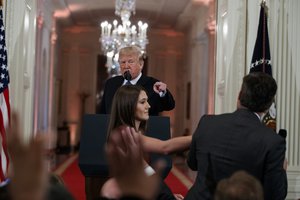 President Donald Trump looks on as a White House aide attempts to take away a microphone from CNN journalist Jim Acosta during a news conference in the East Room of the White House, Wednesday, Nov. 7, 2018, in Washington.