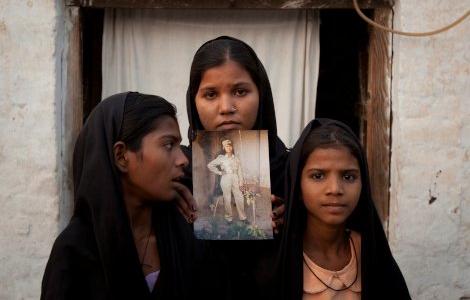 The daughters of Pakistani Christian woman Asia Bibi pose with an image of their mother while standing outside their residence in Sheikhupura located in Pakistan's Punjab Province November 13, 2010. Standing left to right is Esha, 12, Sidra, 18 and Eshum, 10. REUTERS/Adrees Latif