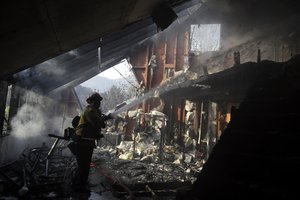 Capt. Adrian Murrieta with the Los Angeles County Fire Dept., hoses down hot spots on a wildfire-ravaged home Saturday, Nov. 10, 2018, in Malibu, California.