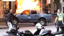 Suspect and police in front of car fire on Bourke Street