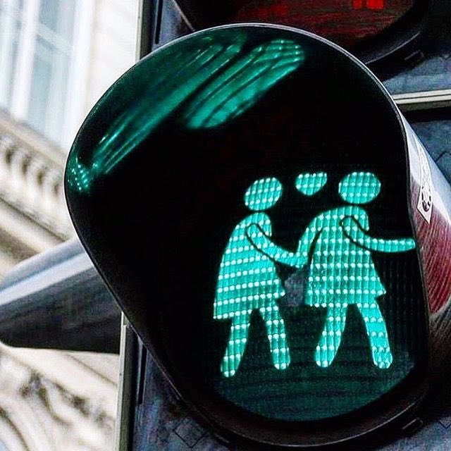 ‪[IMAGE DESCRIPTION Outdoors walk signal with two femmes walking hand-in-hand] ‬