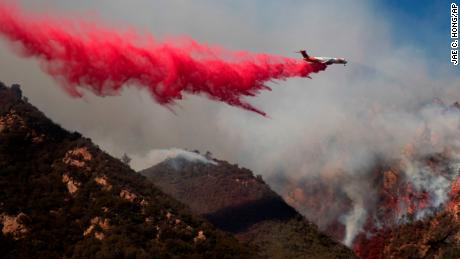 A plane drops fire retardant on a burning hillside Sunday, Nov. 11, 2018, in Malibu, Calif. (AP Photo/Jae C. Hong)