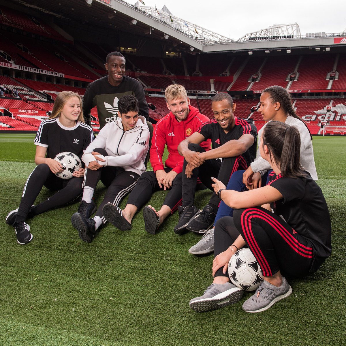 Luke Shaw meeting Foundation participants sat on the edge of the Old Trafford pitch