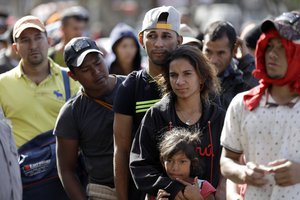 Marvin Ochoa, center, of Honduras, waits in line for a meal behind his wife Diana Marylin Ochoa after they arrived with a Central America migrant caravan to Tijuana, Mexico, Thursday, Nov. 15, 2018