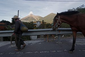 A man leads his horse through San Juan Alotenango, Guatemala, Tuesday, Nov. 20, 2018, backdropped by the Volcan de Fuego, or Volcano of Fire.