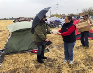 Amy Sheppard accepts banana bread from Margarita and William Bradbury as she packs up items outside her tent in a Walmart parking lot in Chico, Calif., that’s been a makeshift campground for people displaced by wildfire, Wednesday morning, Nov. 21, 2018.