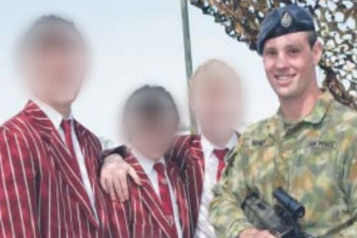 Jared with camouflage uniform and weapon standing beside three boys.