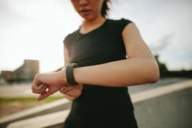 H4MT5P Close up shot of young woman runner using smartwatch outdoors. Fitness female checking her performance. Running at lunch.