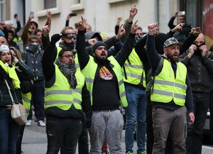 Demonstrators wearing yellow vests gesture towards riot police officers during a visit by French Foreign Minister Jean-Yves Le Drian in Biarritz, southwestern France, Tuesday, Dec. 18, 2018