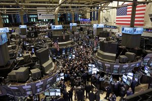 Traders gather near the post where General Motors Co. stock trades at the New York Stock Exchange