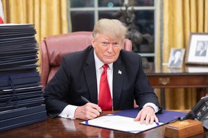 President Donald J. Trump is seen at his desk Friday evening, December 21, 2018, in the Oval Office with a stack of documents awaiting his signature