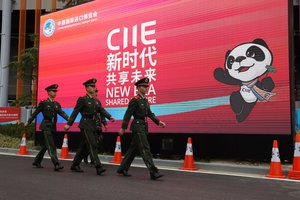 File - In this Nov. 4, 2018, photo, Chinese paramilitary policemen march near a billboard for the China International Import Expo in Shanghai.