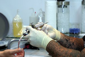 A man prepares to work on a  tattoo on a Marines forearm.