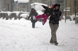 Ted Sullivan flings his daughter, Willa, 3, through the air while playing in the snow on Broad Street in Lower Manhattan