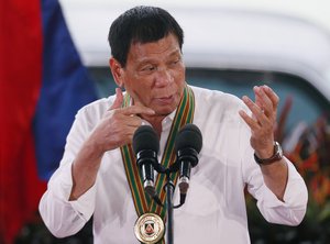 In this Tuesday Oct. 4, 2016 photo, Philippine President Rodrigo Duterte gestures with a firing stance as he announces issuing side arms to army troopers during his visit to its headquarters in suburban Taguig city, east of Manila, Philippines.