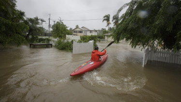 A local resident is seen kayaking in flood waters at her home in Hermit Park Townsville on Sunday.