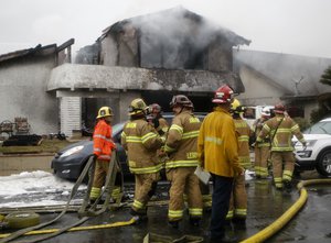 Firefighters suppress a fire at the scene of a deadly plane crash in the residential neighborhood of Yorba Linda, Calif., Sunday, Feb. 3, 2019.