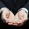 Businessman with hands cupped in front of him.