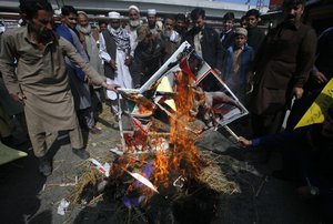 Pakistani protesters burn an effigy and posters of Indian Prime Minister Narendra Modi during a rally to denounce the recent killings by Indian forces in the disputed Himalayan region of Kashmir, in Peshawar, Pakistan, Monday, Feb. 25, 2019.