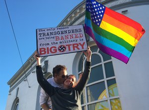 Nick Rondoletto, left, and Doug Thorogood, a couple from San Francisco, wave a rainbow flag and hold a sign against a proposed ban of transgendered people in the military at a protest in the Castro District, Wednesday, July 26, 2017