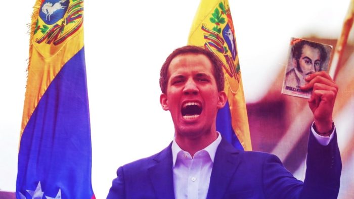 Opposition leader Jaun Guaido declaring himself president at a rally holding a copy of the Venezuelan constitution.