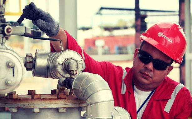 Oil worker wearing PVDSA hat turning valve.