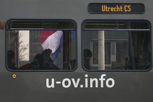 A tram passes a Dutch flag flying half-staff at the site of a shooting incident in a tram in Utrecht, Netherlands, Tuesday, March 19, 2019.