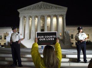 A demonstrator protests in front of the Supreme Court as President Donald Trump announces Judge Brett Kavanaugh as his Supreme Court nominee in Washington, Monday, July 9, 2018.