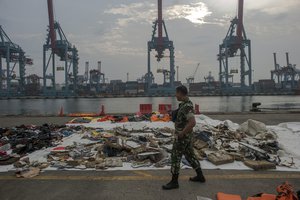 An Indonesian soldiers walk past debris retrieved from the waters where Lion Air flight JT 610 is believed to have crashed at Tanjung Priok Port in Jakarta, Indonesia, Wednesday, Oct. 31, 2018.