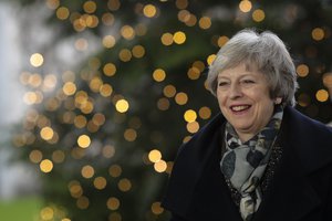 In this Dec. 11, 2018 photo British Prime Minister Theresa May smiles in front of a Christmas tree when arriving for a meeting with German Chancellor Angela Merkel at the chancellery in Berlin