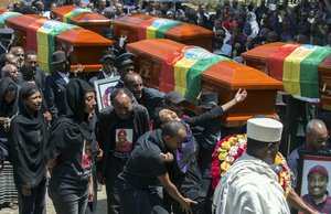 Relatives grieve next to empty caskets draped with the national flag at a mass funeral at the Holy Trinity Cathedral in Addis Ababa, Ethiopia Sunday, March 17, 2019. Thousands of Ethiopians have turned out to a mass funeral ceremony in the capital one week after the Ethiopian Airlines plane crash.