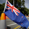 New Zealand's flag is on display as volunteers move flowers away near the Al Noor mosque in Christchurch, New Zealand, Thursday, March 21, 2019. Thousands of people were expected to come together for an emotional Friday prayer service led by the imam of one of the two New Zealand mosques where 50 worshippers were killed in a white supremacist attack on Friday March 15. (AP Photo/Vincent Thian)